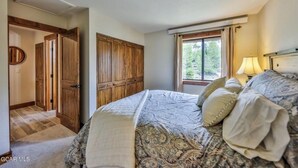 Ein Schlafzimmer mit einem großen Bett, einem Holzschrank und einem Fenster mit Vorhängen.