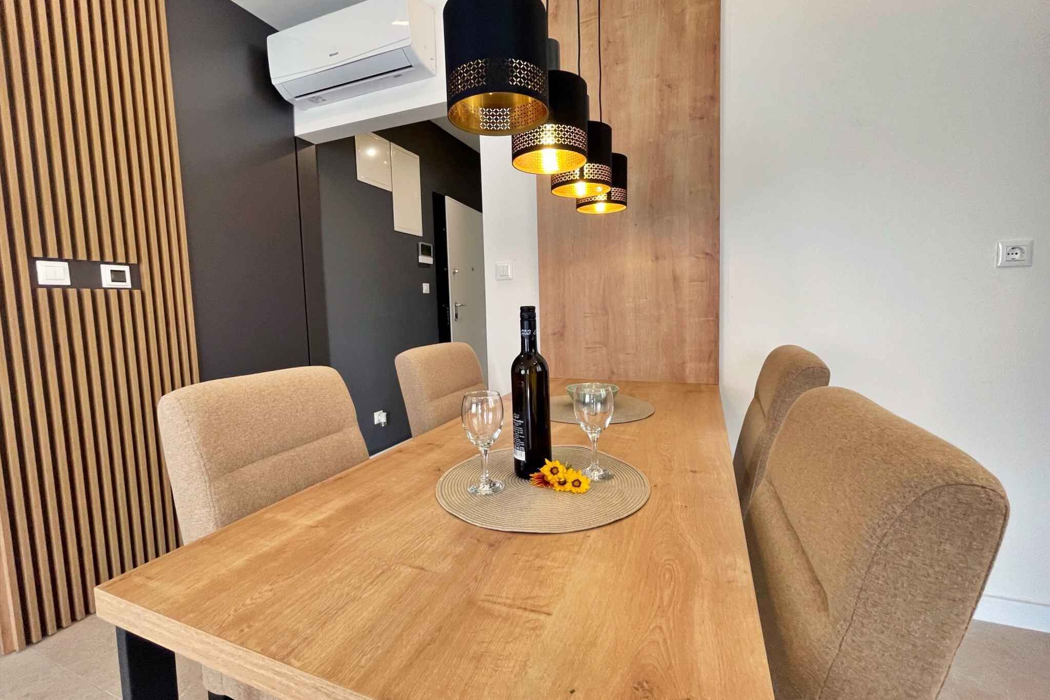 A dining area with a wooden table, four beige chairs, and a bottle of wine.