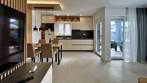 A modern kitchen with a dining area, a TV, and a view to the outside. - Holiday apartment with swimming pool and sea view (Šilo)