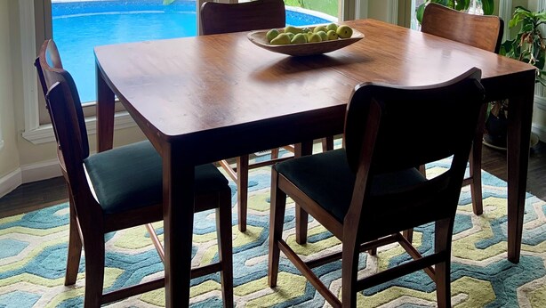 A dining area with a wooden table and chairs, large windows with a view of a swimming pool and greenery, and a flag outside. - The Dream Lakehouse  (Florence)