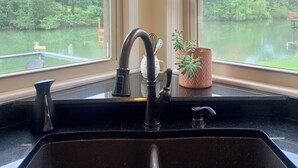 A kitchen with a black sink, two windows, and a view of a body of water. - The Dream Lakehouse  (Florence)