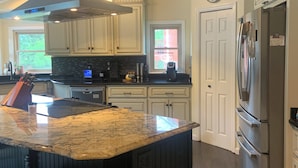 A kitchen with a central island, dark wood paneling, a stainless steel refrigerator, and a window with a view. - The Dream Lakehouse  (Florence)