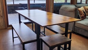 A wooden dining table with benches, a sofa, and a view of a lake through large windows.