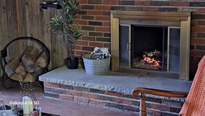 A fireplace with a stone surround, a potted plant, and a wicker chair.