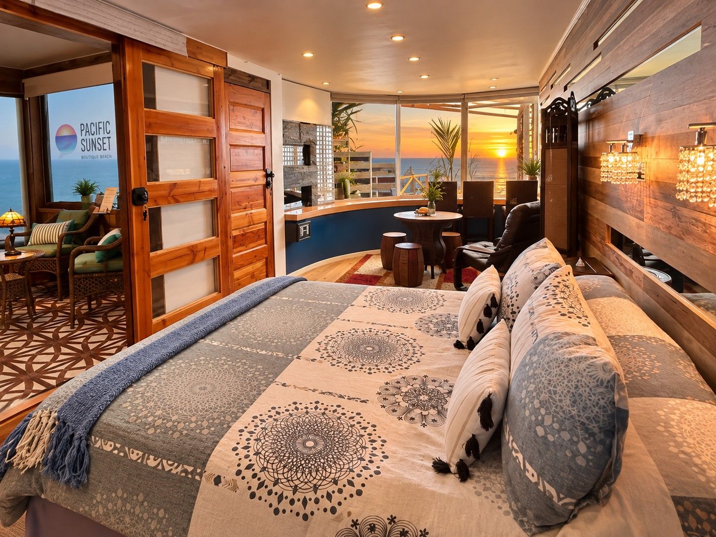 A hotel room with a large bed, a seating area with a view of the sunset, and a wooden door.