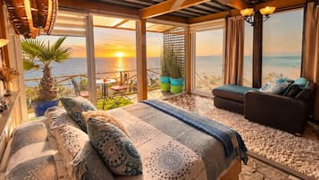 Een slaapkamer met een bed, een bank en een balkon met uitzicht op zee.