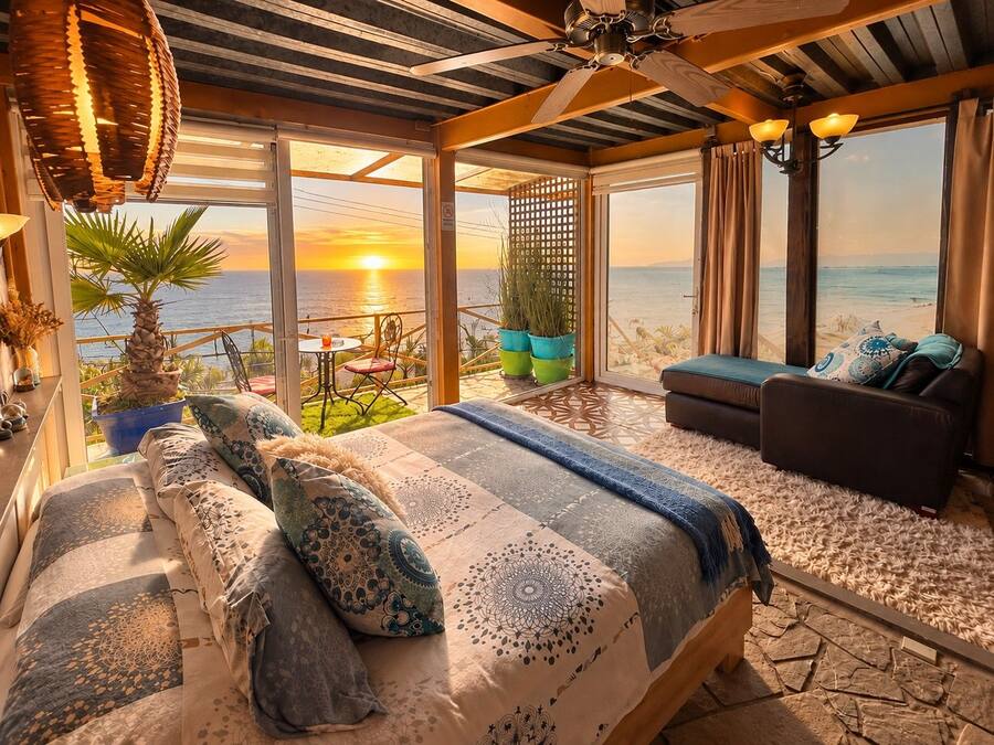 Un dormitorio con cama, sofá y balcón con vista al mar.