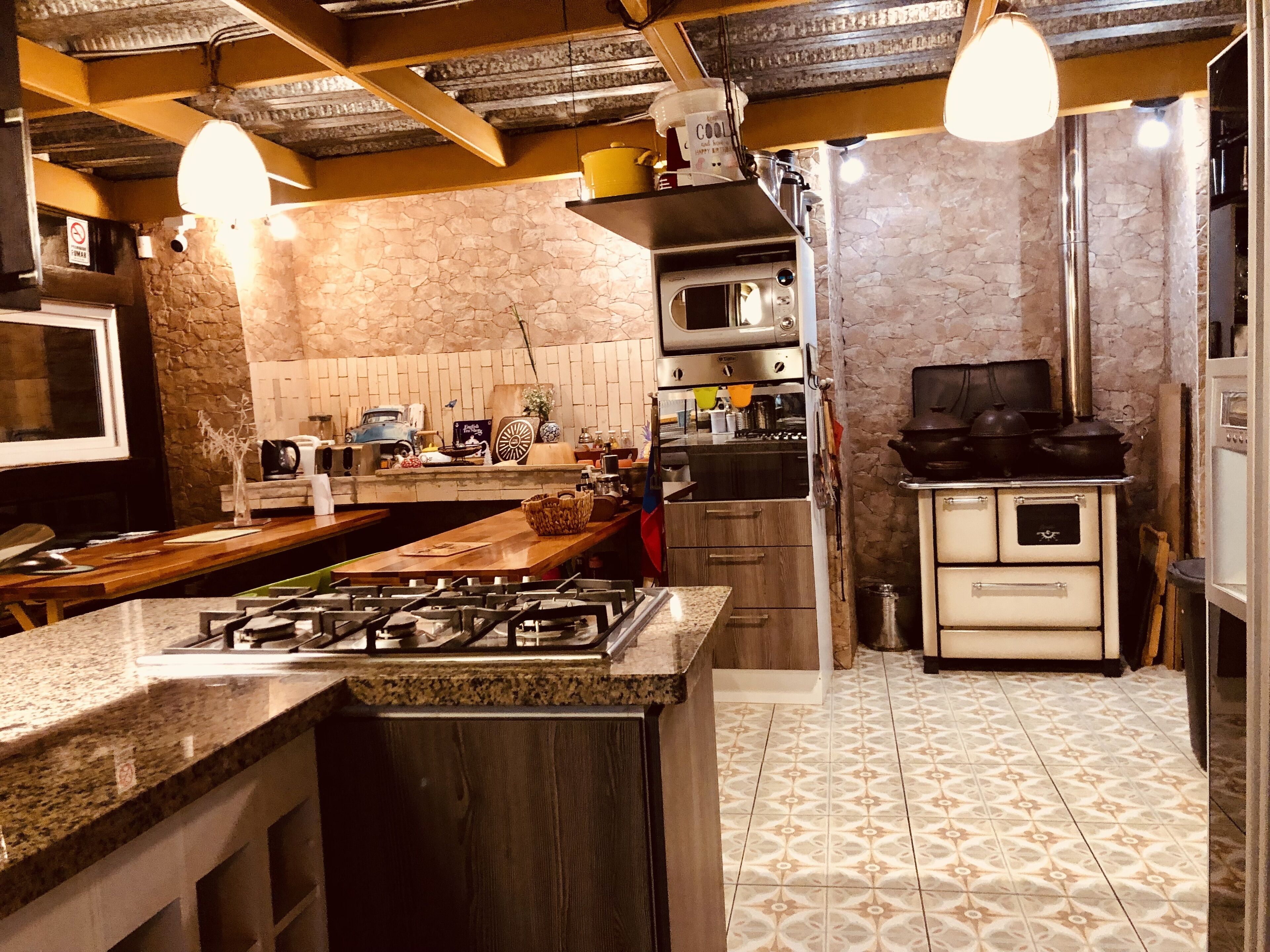 Cocina con estufa a gas, microondas, horno y protector de pared de piedra.