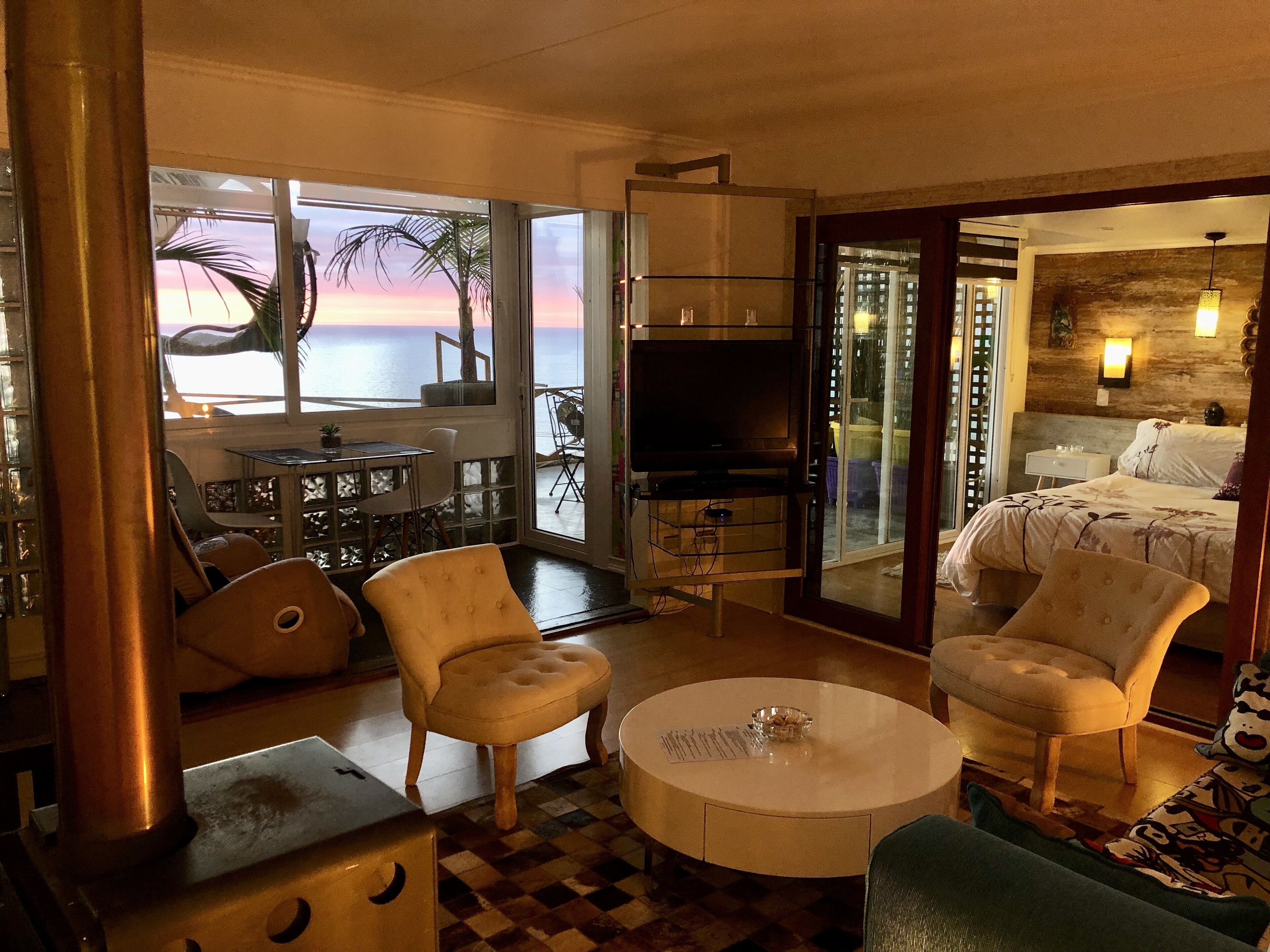 Une chambre d’hôtel avec un balcon, une télévision, un lit et deux fauteuils.