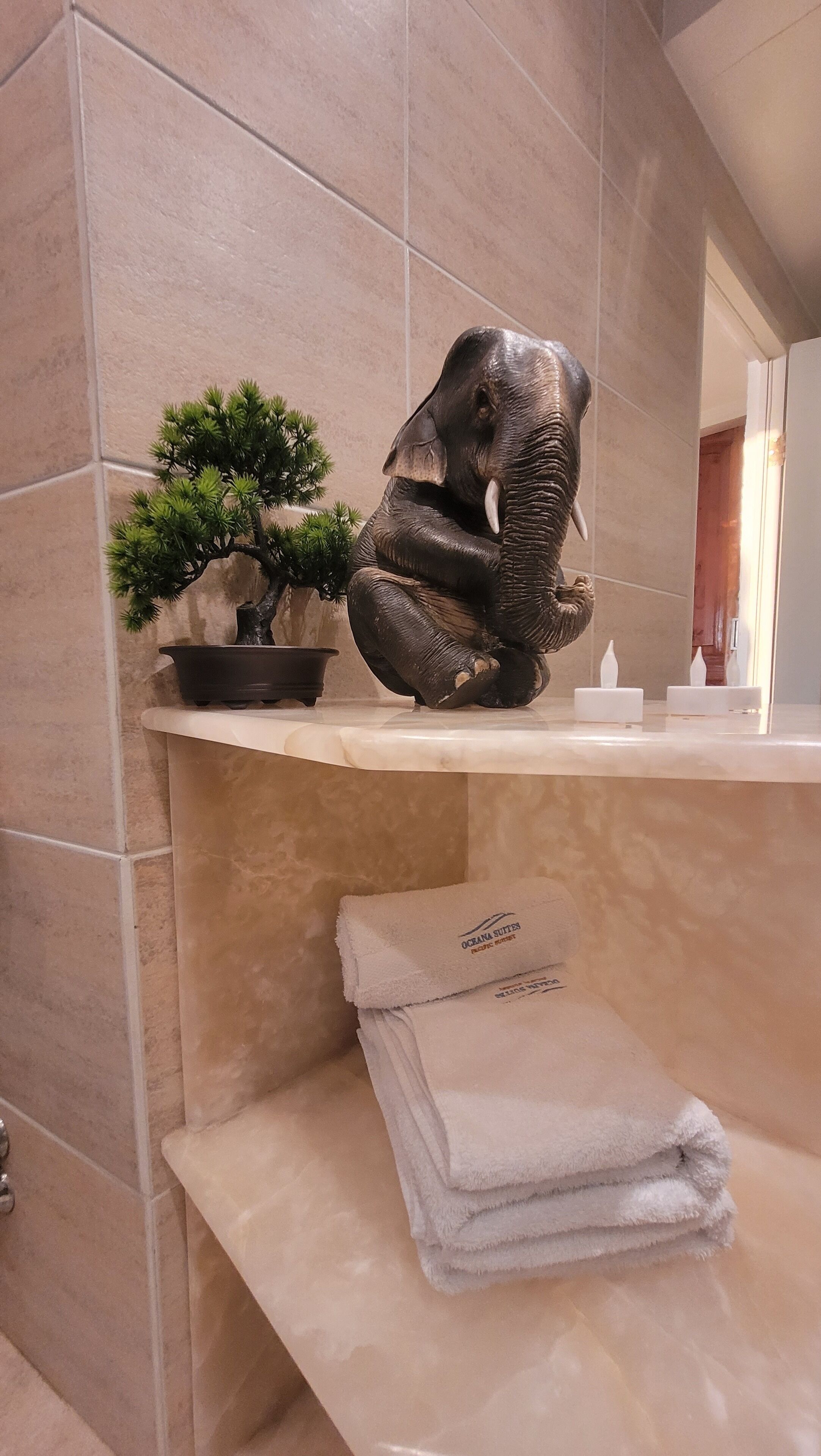 A bathroom with a marble sink, a small potted plant, and a folded towel.