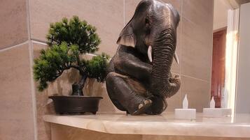 A bathroom with a marble sink, a small potted plant, and a folded towel.