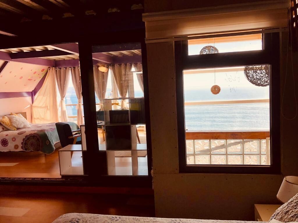 Una habitación con cama, escritorio y ventana con vista a la playa.
