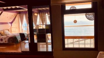 Una habitación con cama, escritorio y ventana con vista a la playa.