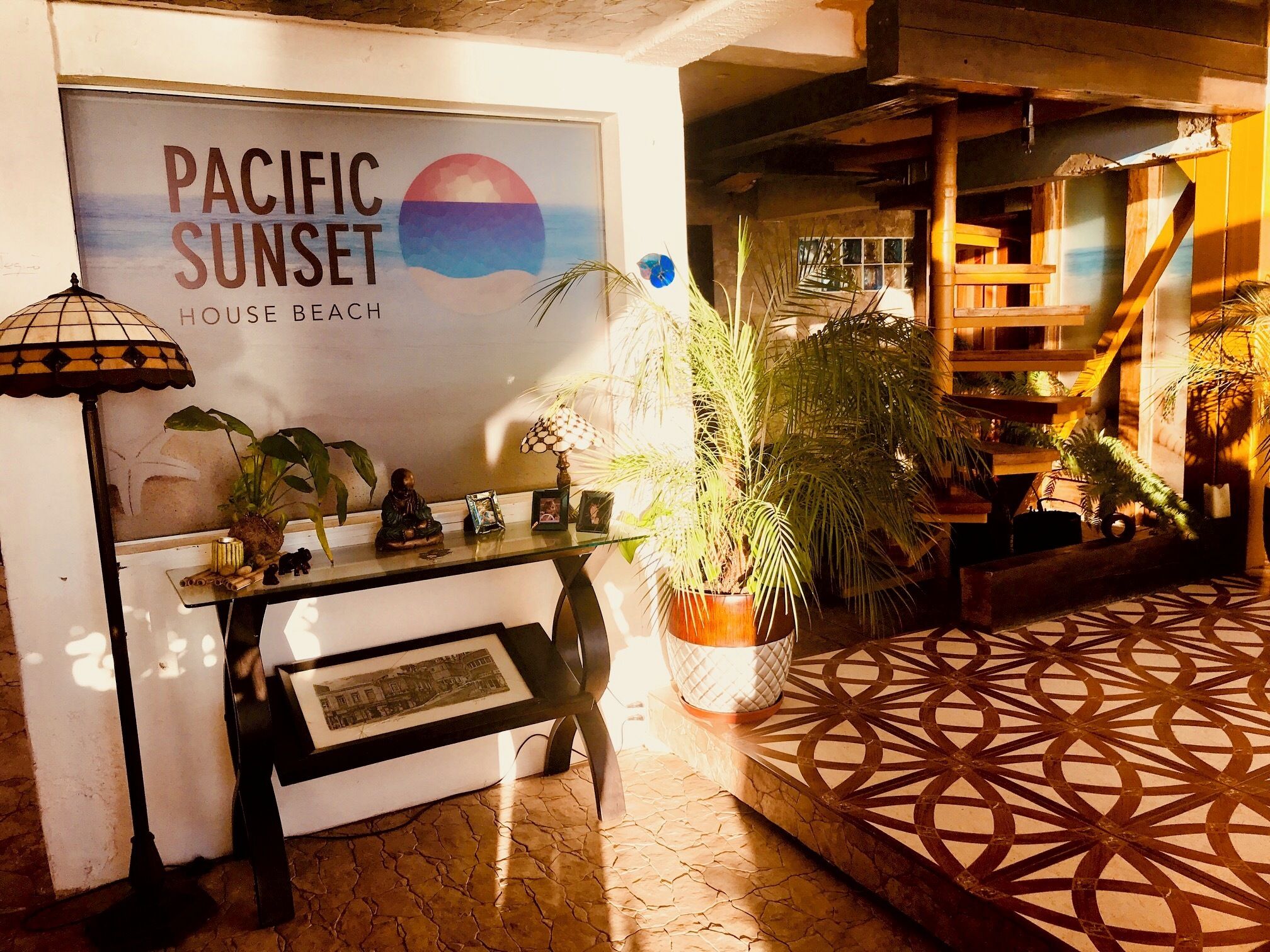 Una habitación con un cartel de Atardecer Pacífico, un escritorio con una lámpara, una silla y una planta en maceta.