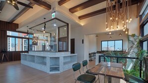 Un interior moderno con una isla central, vigas de madera en el techo y un comedor con sillas tapizadas en verde.