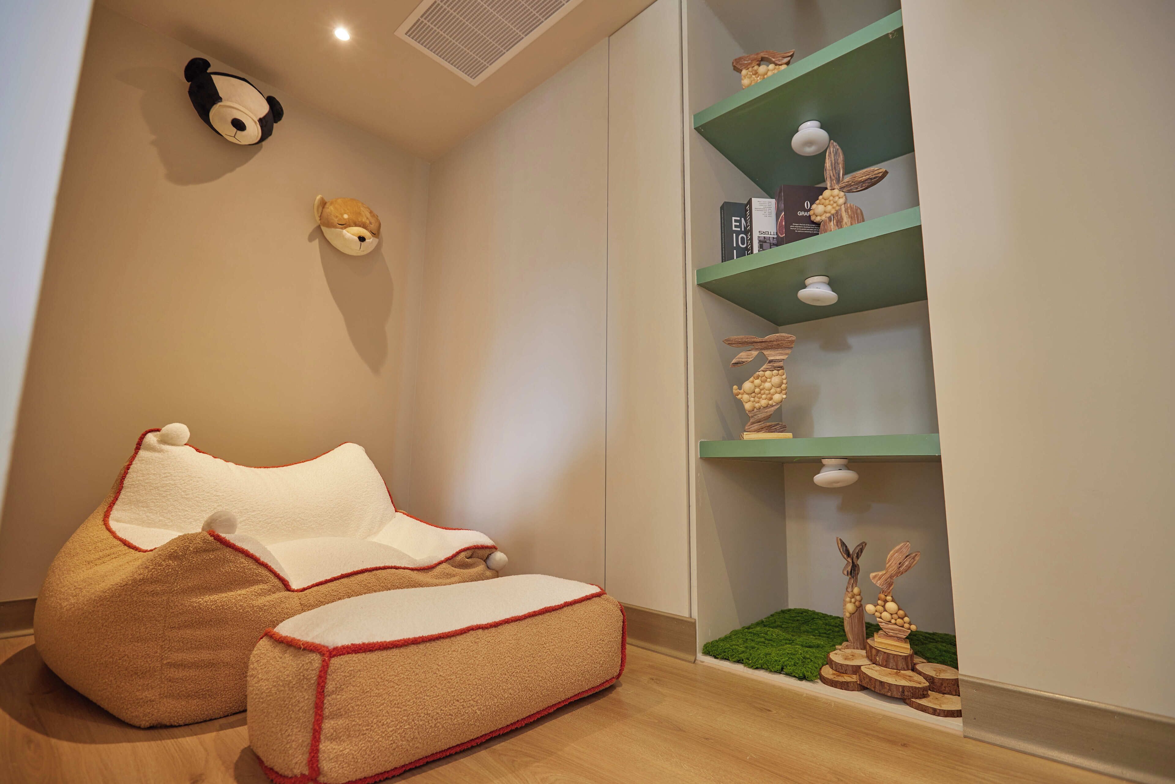 Una habitación acogedora con un sillón orejero, una estantería con adornos y un peluche de panda en la pared.