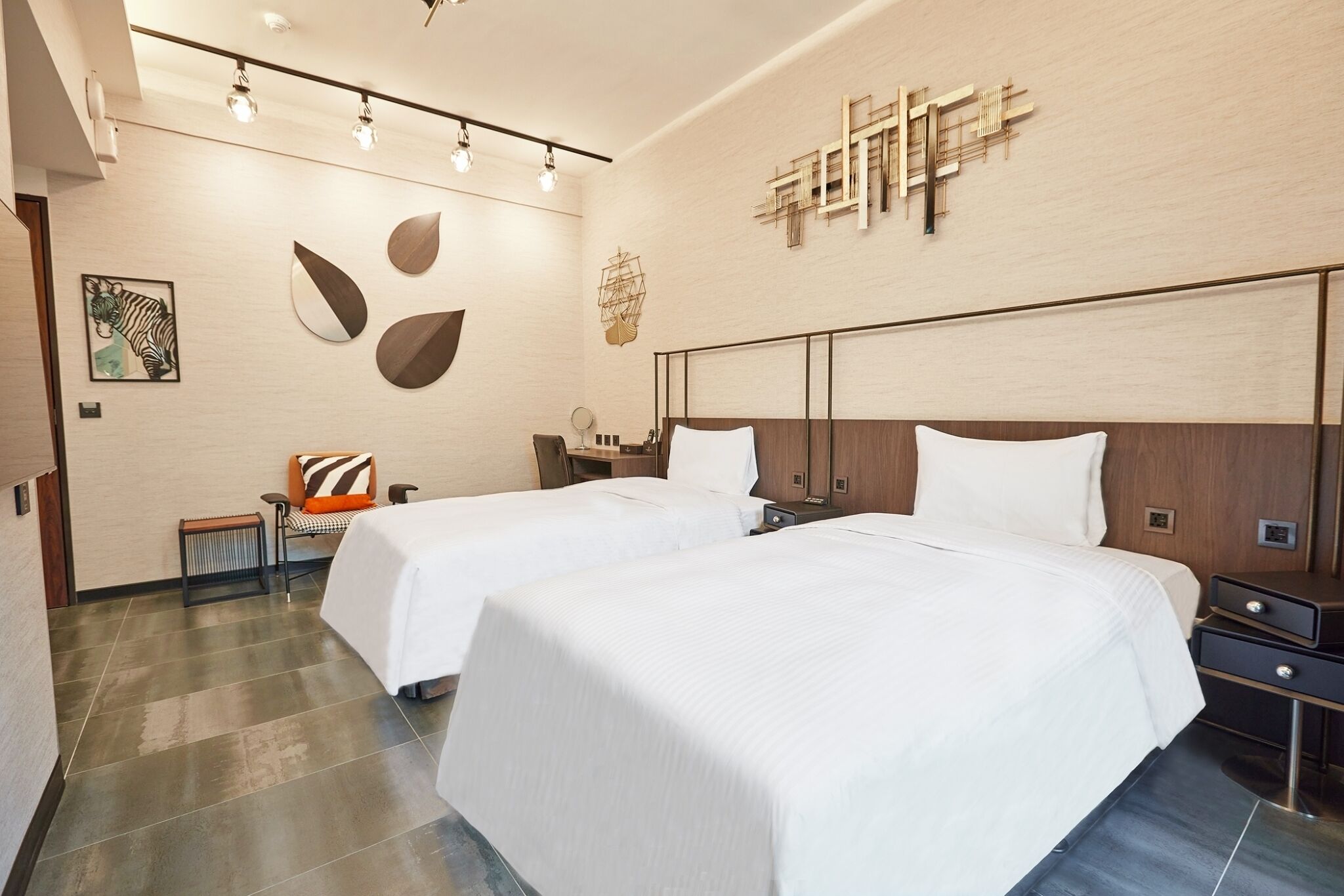 Een hotelkamer met twee bedden, een houten hoofdbord, een kunstwerk aan de muur en een bankje met een kussen.