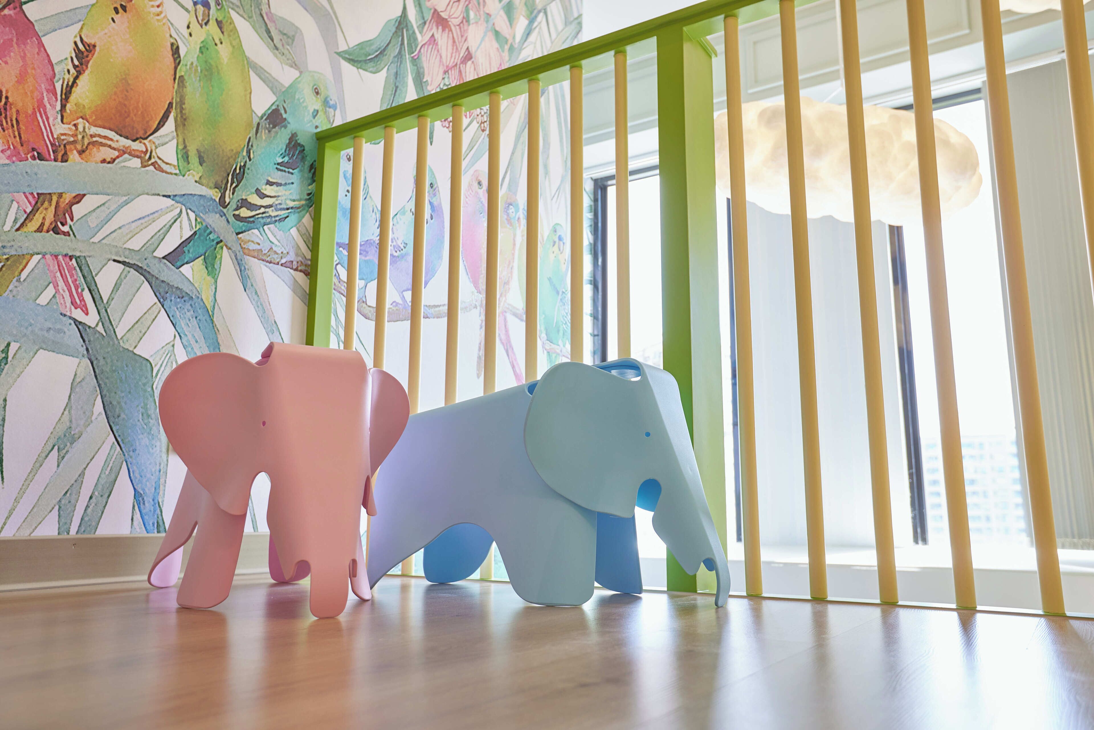 A room with a wooden floor, a green railing, and a wall with a bird mural.