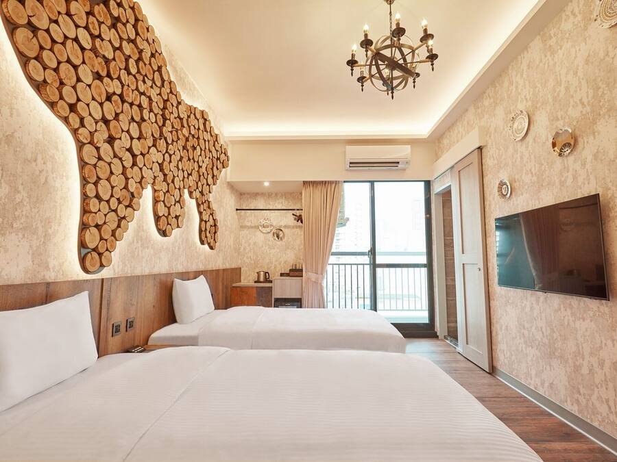 Une chambre d’hôtel avec deux lits, un lustre, une télévision et une grande fenêtre avec des rideaux.