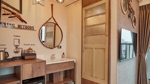 Un baño moderno con tocador de madera, espejo y un refrigerador pequeño.