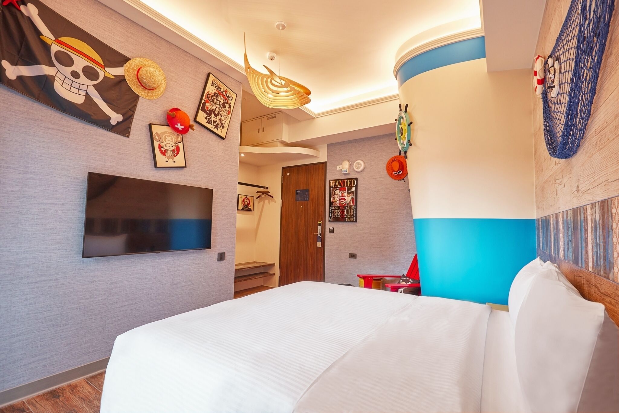 Una habitación de hotel moderna con una cama grande, un televisor de pantalla plana y decoración con motivos náuticos.