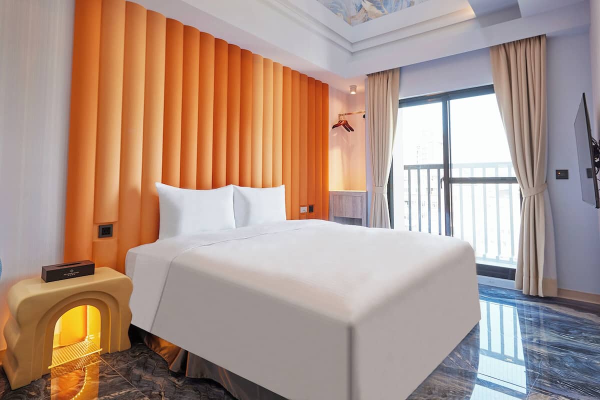 A hotel room with a large bed, a built-in heater, a ceiling with a floral design, and a view of the outside through a large window.