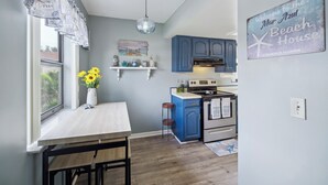 A kitchen with blue cabinets, a white countertop, and a hanging light fixture. - Cocoa Beach Vacation Rental - Walk to Pier! (Cocoa Beach)