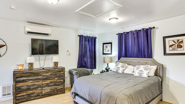 A bedroom with a bed, dresser, TV, and artwork. - Walkable Paradise: Downtown Puyallup Studio! (Puyallup)