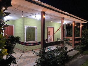 A covered outdoor area with a green wall, a window with metal bars, and a hammock.