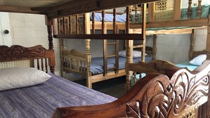 A room with a wooden bed with intricate carvings, a bunk bed, and a window with a wooden lattice design. - Nanda Parbat Hostal (San Rafael Cedros)