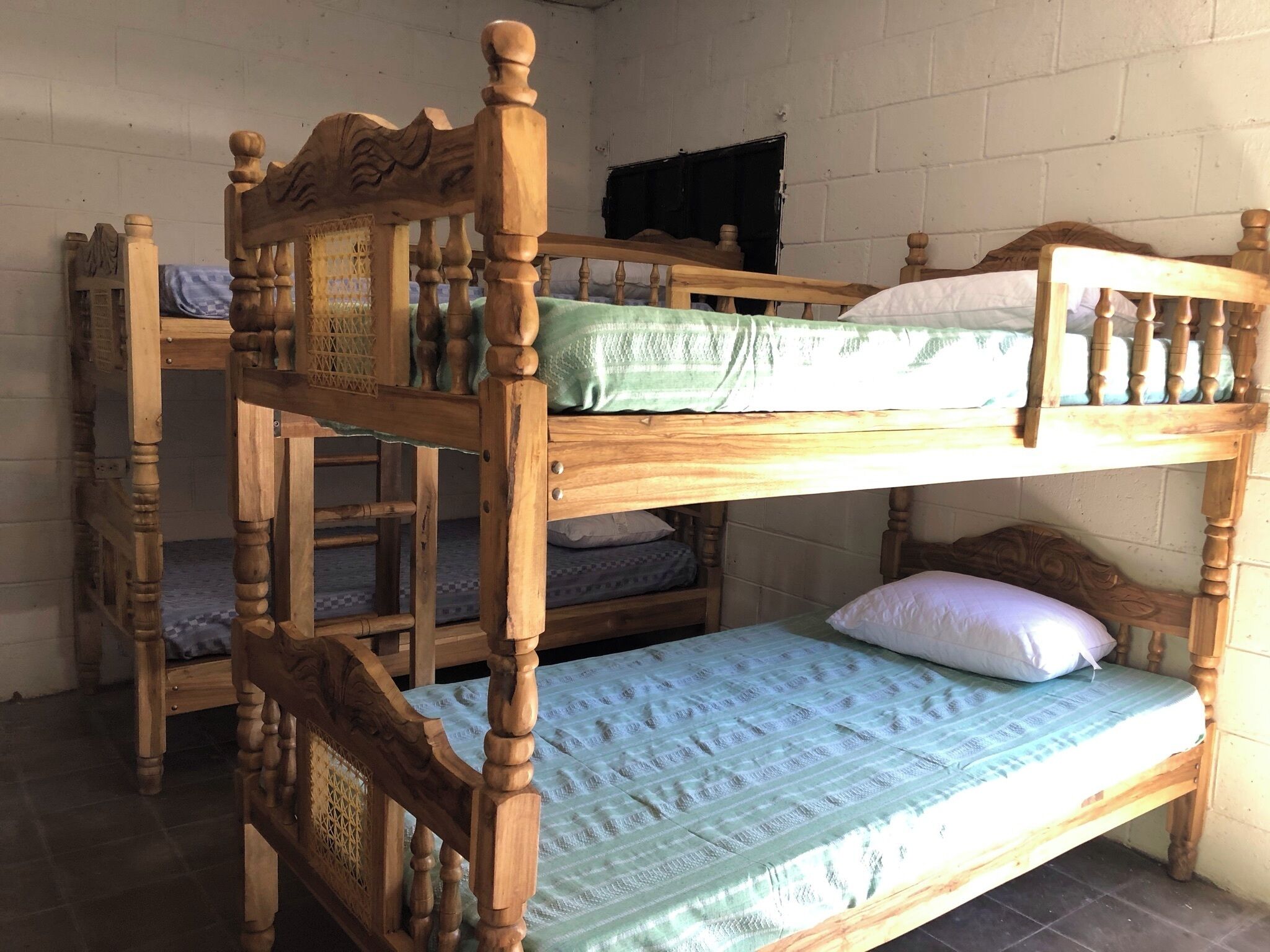 Un lit superposé avec une tête de lit en bois et un lit inférieur doté d’un matelas vert.