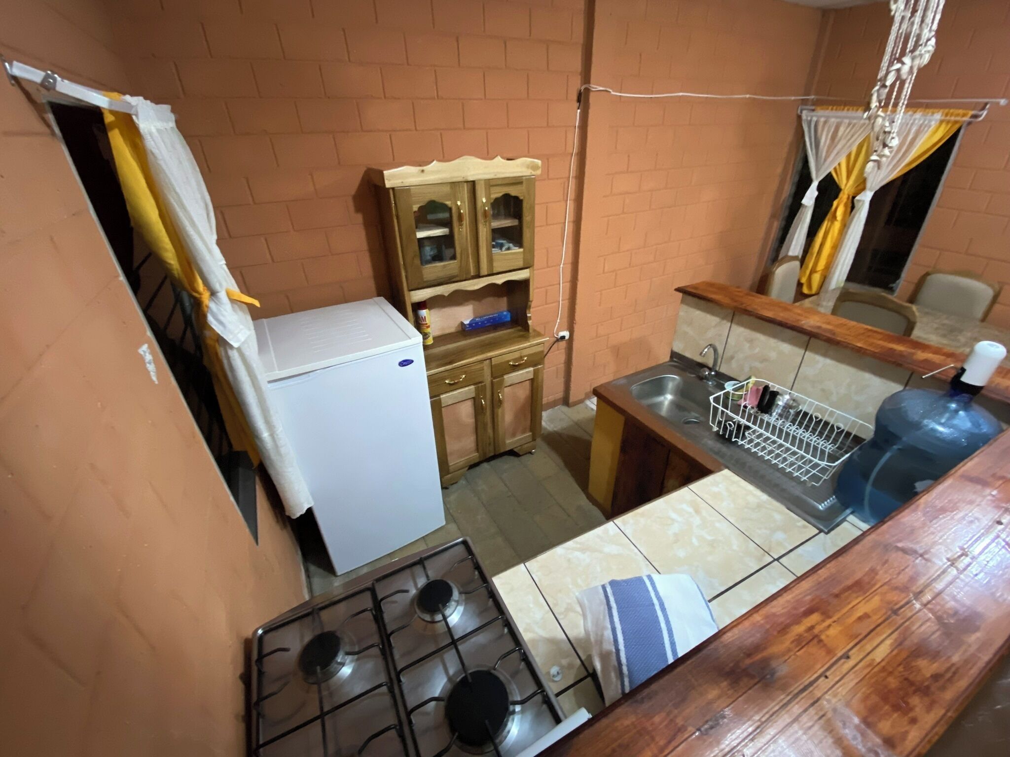 A compact kitchen with a gas stove, a small refrigerator, wooden cabinets, and a sink.