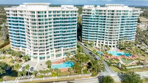 A high-rise hotel with multiple balconies, a swimming pool, and a landscaped area. - Full Ocean View - SERENE SANDCASTLE 2 Bed/2 Bath (Gulfport)
