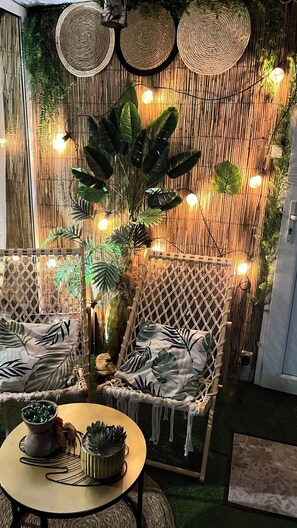 A cozy seating area with wicker furniture, a large potted plant, and ambient lighting. - Spacieuse Maison vue sur la Loire (Saint-Clément-des-Levées)