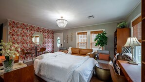 Une chambre à coucher avec un grand lit, un bureau, une chaise, une commode, un miroir et un lustre.