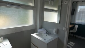 Un baño con un lavamanos blanco, un espejo y una ventana.