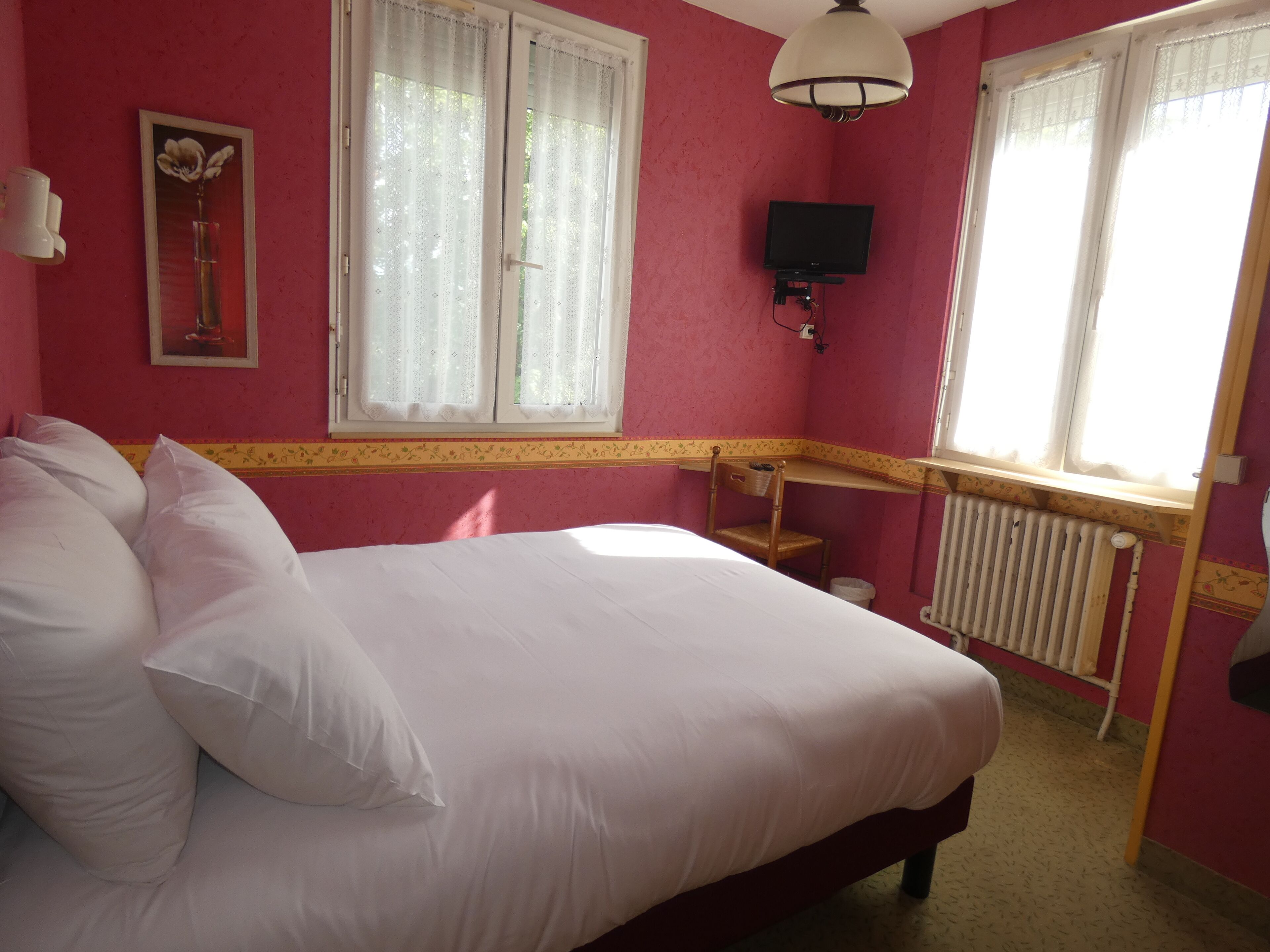 A bedroom with a bed, a television, and a radiator.