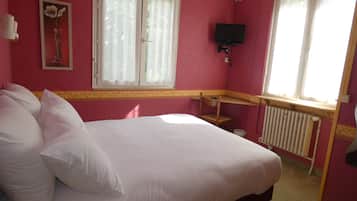 A bedroom with a bed, a television, and a radiator.