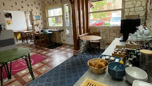 Un rincón acogedor para desayunar, con una mesa de madera, una tabla de cortar con pan y un bufé con platos y tazones.