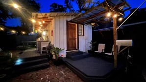A rustic outdoor area with a stone patio, a wooden door, and a small porch with a chair. - Relaxing garden cottage with sauna
 (Shreveport)