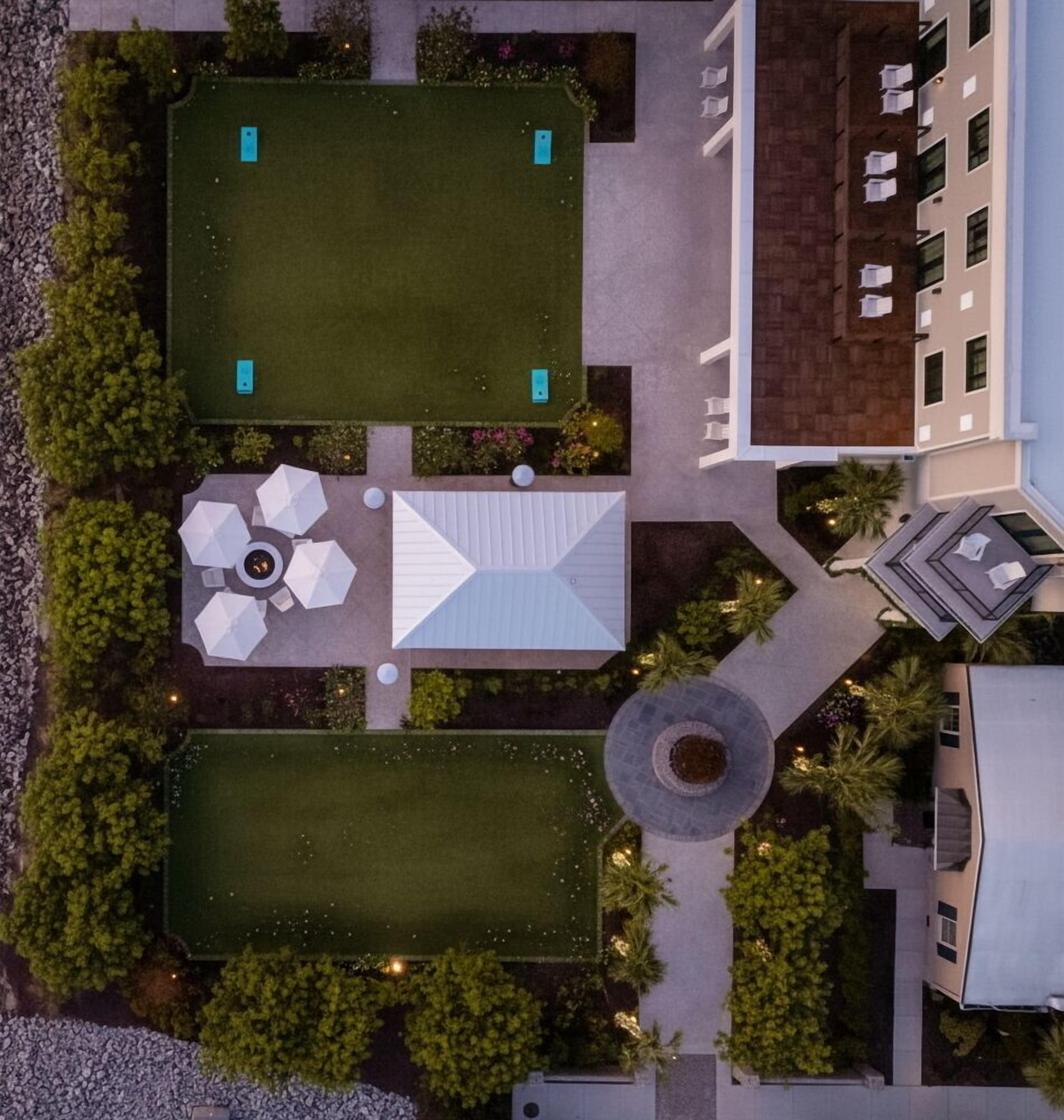 An aerial view of a hotel with two large rectangular outdoor areas, a circular garden feature, and a building with multiple windows.