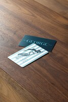 Dos tarjetas de visita sobre una mesa de madera.