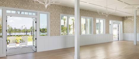 Una habitación espaciosa con ventanas amplias, suelo de madera y vistas a un lago.