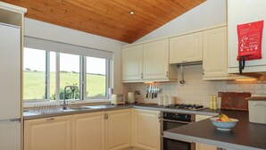 Una cocina moderna con armarios blancos, techo de madera, ventana con vistas al exterior y un letrero de seguridad rojo.