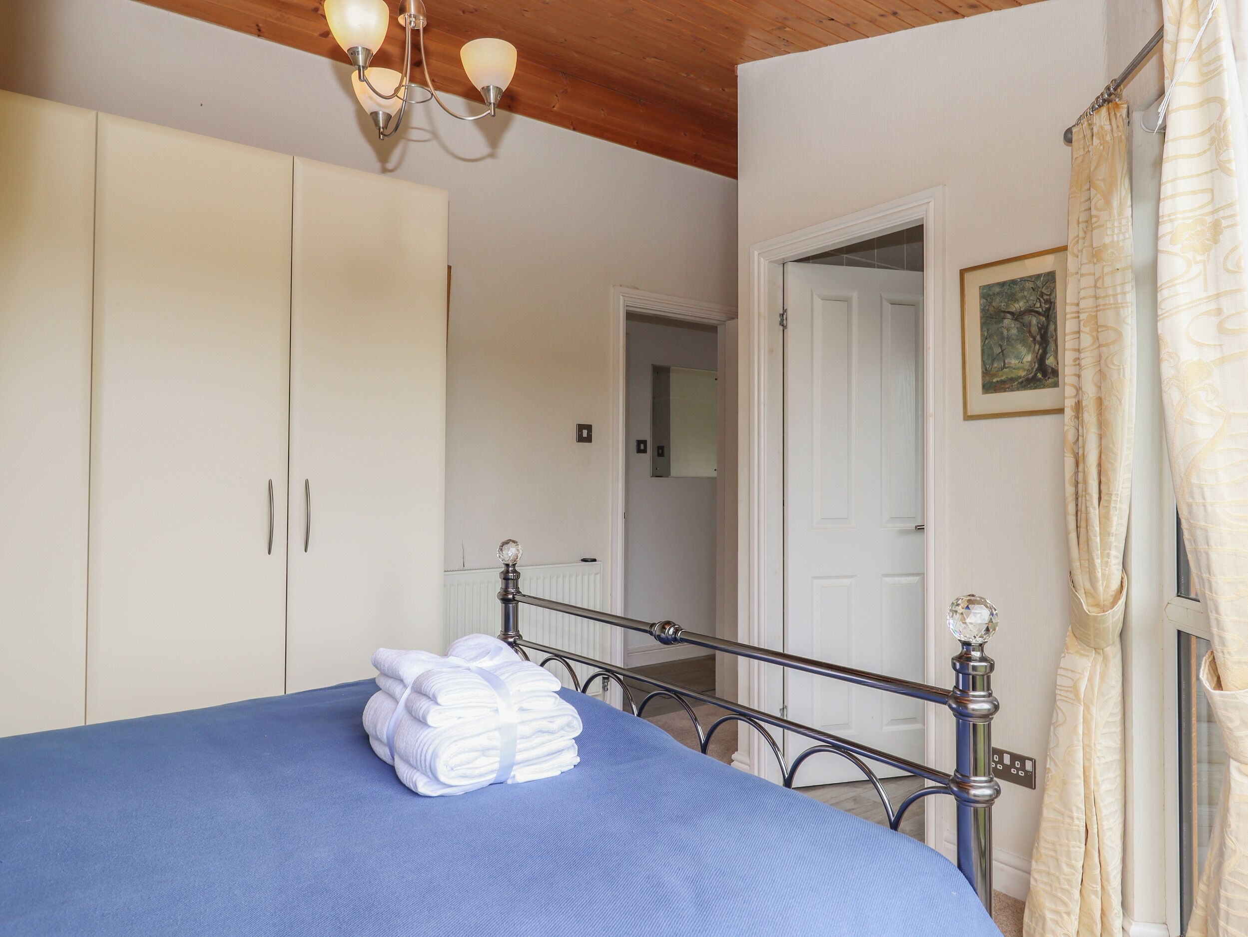 Une chambre à coucher comprenant un lit, une armoire, un miroir et une porte donnant sur une autre pièce.
