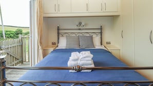 Un dormitorio con una cama, techo de madera y vistas al exterior.