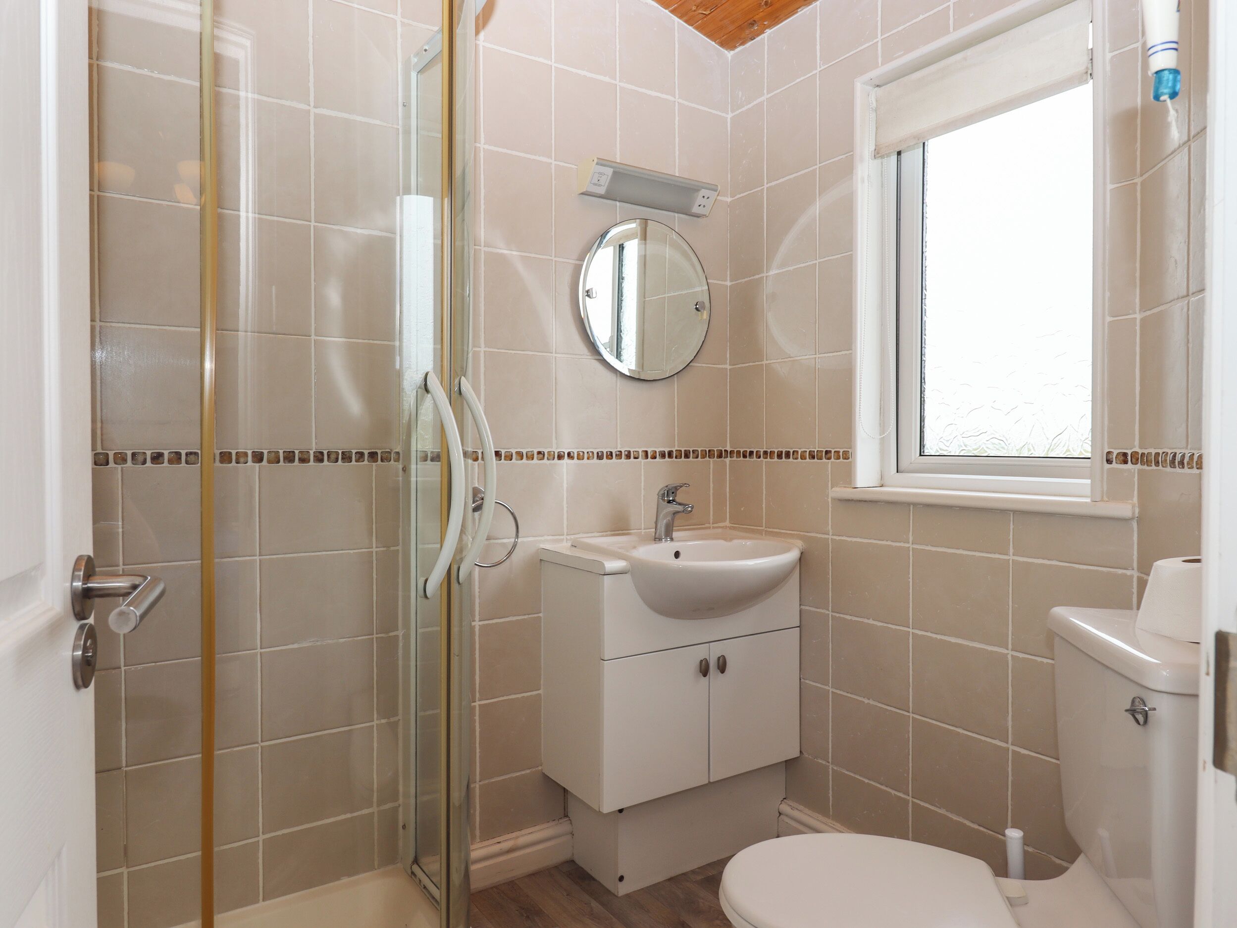Un baño con cabina de ducha de vidrio, un lavabo con espejo y un inodoro.
