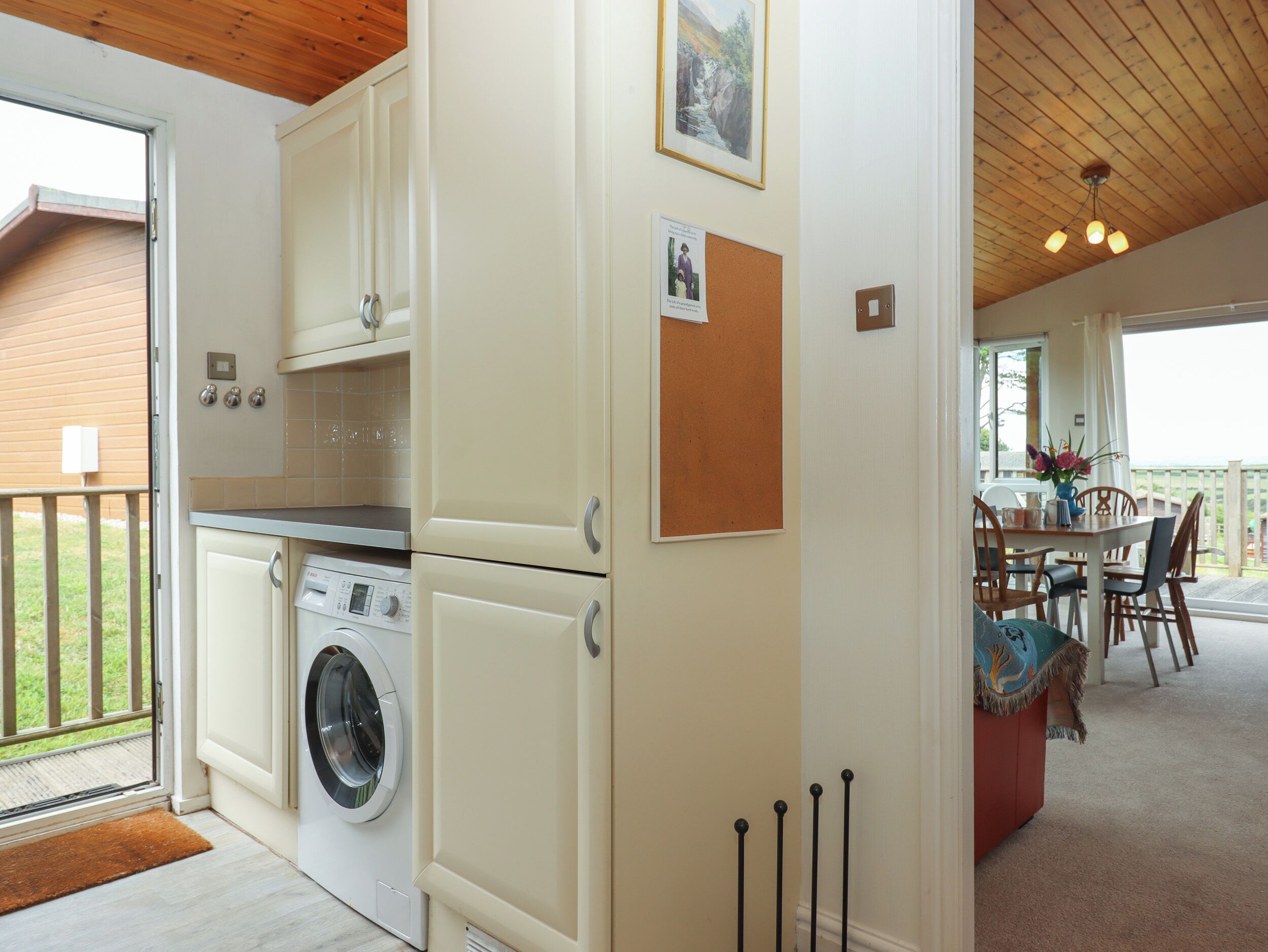 A compact kitchen with a washing machine, a dining area with a table and chairs, and a view of the outdoors.