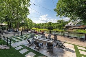 A patio area with Adirondack chairs, a small fire pit, and a view of a bridge and greenery. - 3 Bedroom Suite + Loft, Second Floor (Helena)