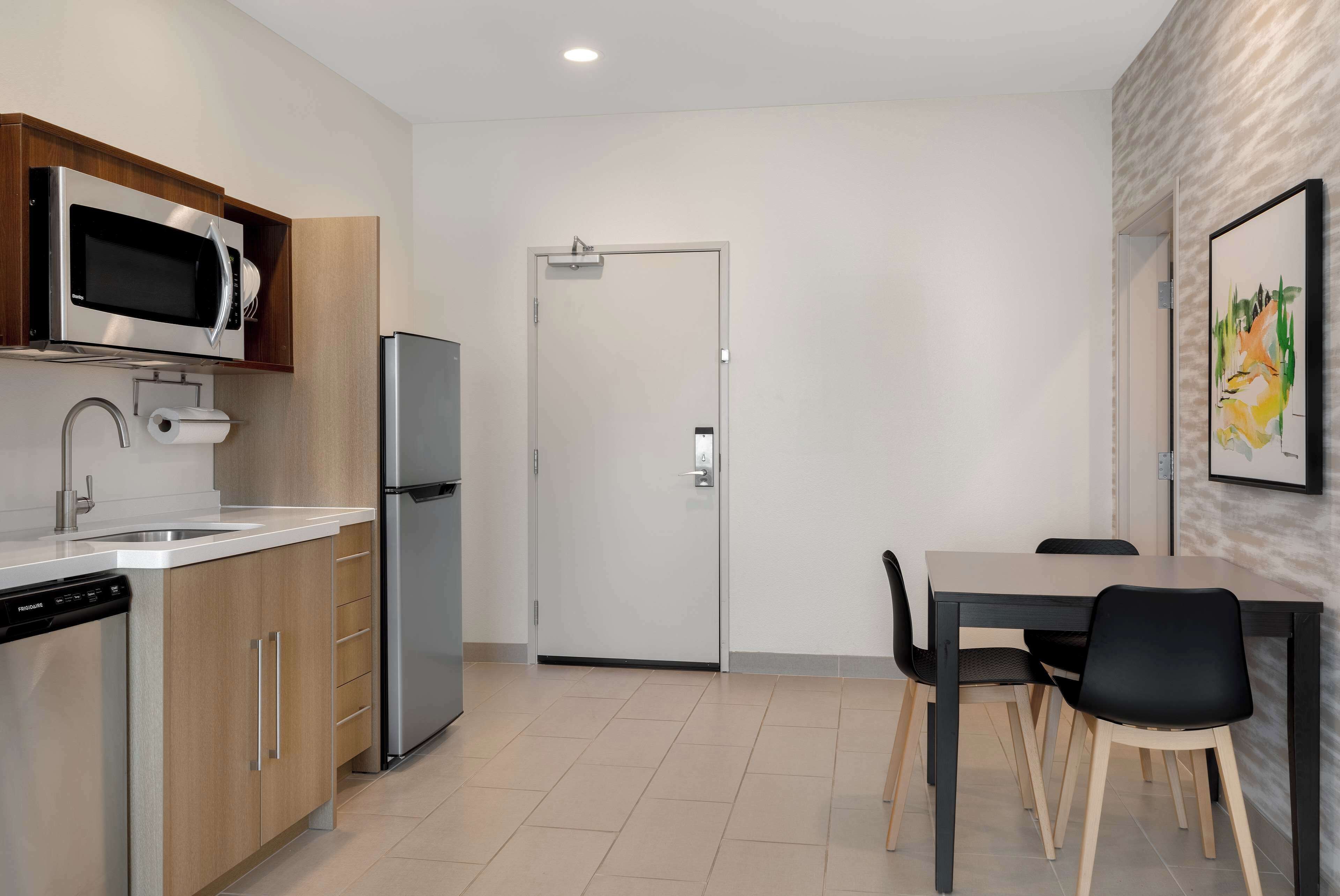 A modern kitchen with a built-in microwave, dishwasher, and refrigerator. There is a dining area with a table and chairs.